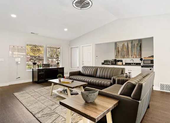 A modern living room with a brown leather couch and a wooden coffee table.