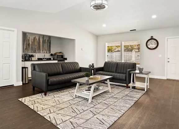 A living room with two black sofas and a coffee table.
