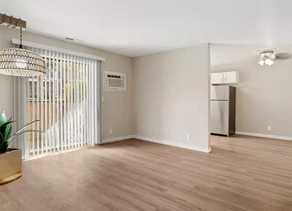 A room with a wooden floor and a window with blinds.