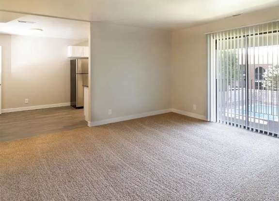 A carpeted room with a sliding glass door leading to a balcony.