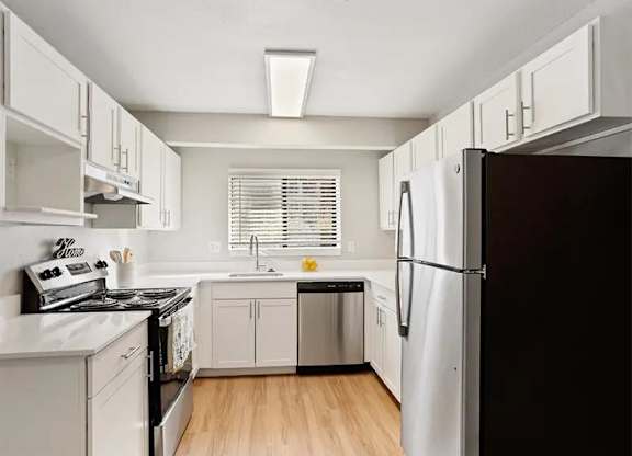 A kitchen with a black refrigerator and white cabinets.