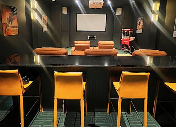 A black table with a white screen and four orange chairs.