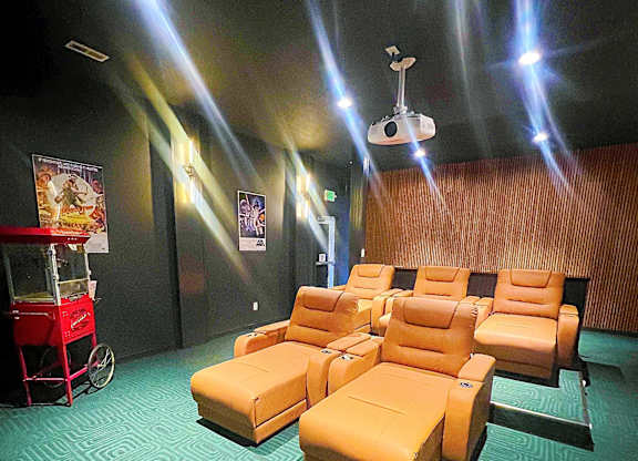 A row of orange chairs are arranged in a room with a patterned carpet.