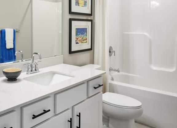 A white bathroom with a toilet, sink, and a shower.