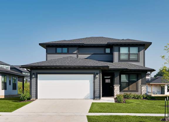 A modern house with a grey roof and a white garage door.