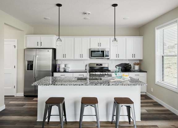 A kitchen with white cabinets and a granite countertop.