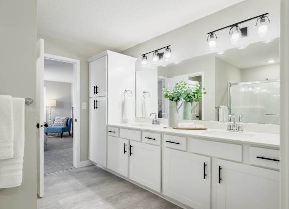 A white bathroom with a mirror and lights above it.