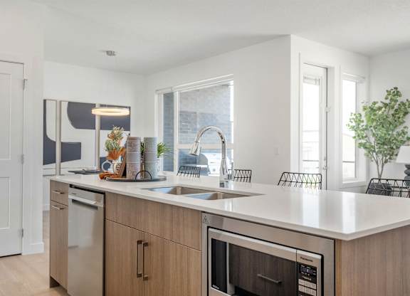 A modern kitchen with a white countertop and stainless steel appliances.