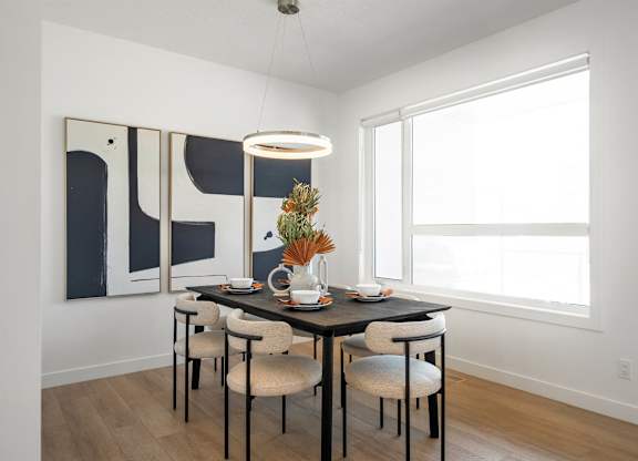 A dining room with a table set for two and a modern art piece on the wall.