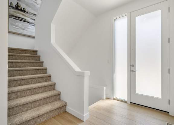 A staircase with a carpeted runner and a white wall.