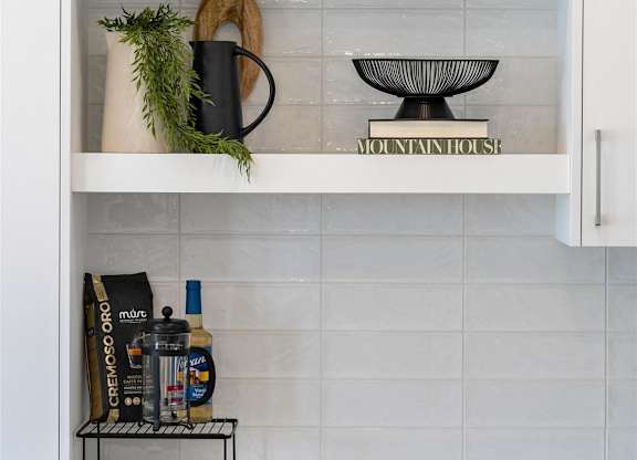 A kitchen cabinet with a white interior and shelves containing various items.