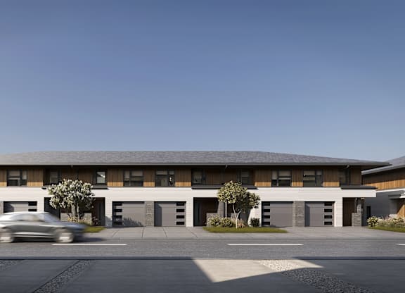 A grey car is driving past a large building.