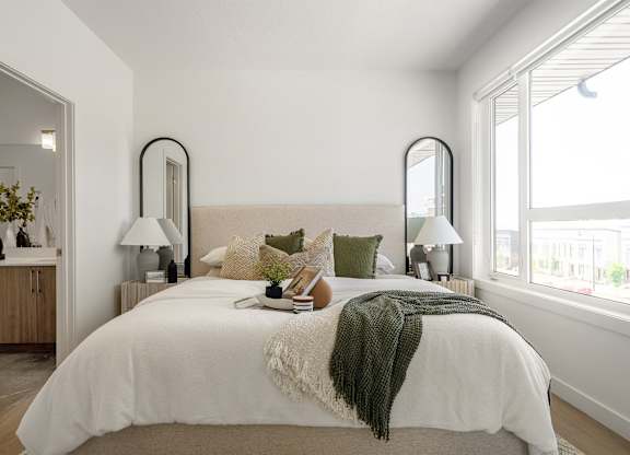 A bedroom with a large bed and two lamps.