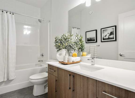 A bathroom with a white sink, toilet, and a shower with a white curtain.