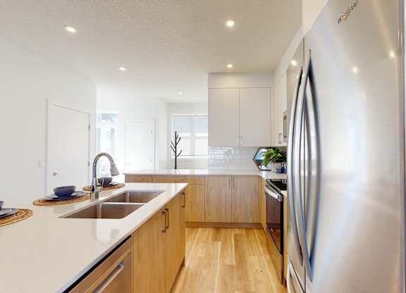 A modern kitchen with a stainless steel refrigerator and wooden cabinets.
