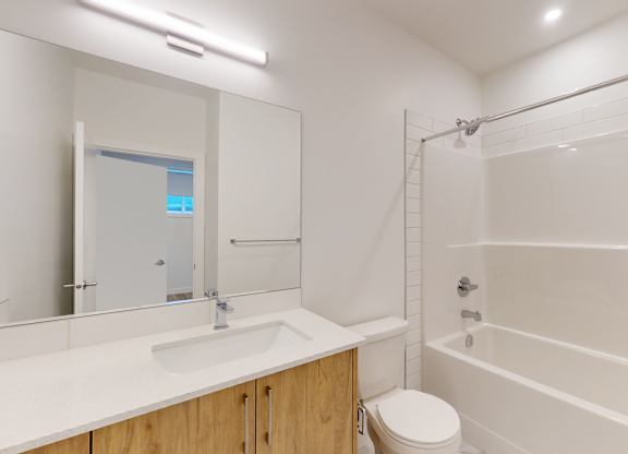 A white bathroom with a toilet, sink, and shower.