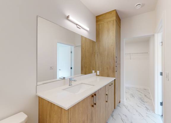 A bathroom with a sink, mirror, and wooden cabinetry.