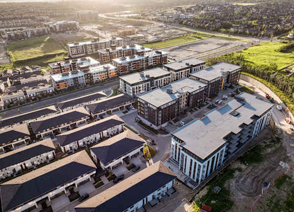 A large building complex with a mix of modern and traditional architecture is surrounded by smaller buildings and greenery.