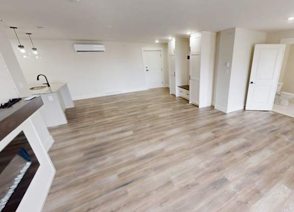 A spacious room with wooden flooring and white walls.