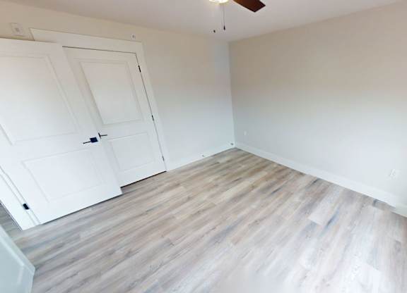 A room with a white door and wooden flooring.