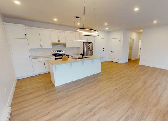 A kitchen with white cabinets and a wooden floor.