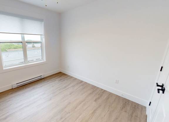 A room with a window and wooden flooring.