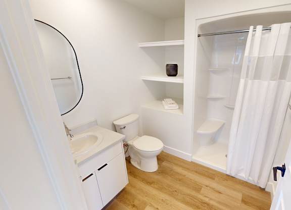 A white bathroom with a toilet, sink, and a shower with a white curtain.