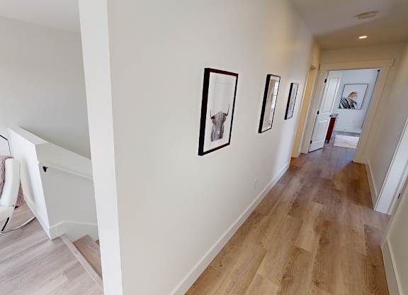 A hallway with a chair and pictures on the wall.