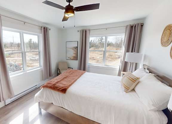 A bedroom with a large bed and a ceiling fan.