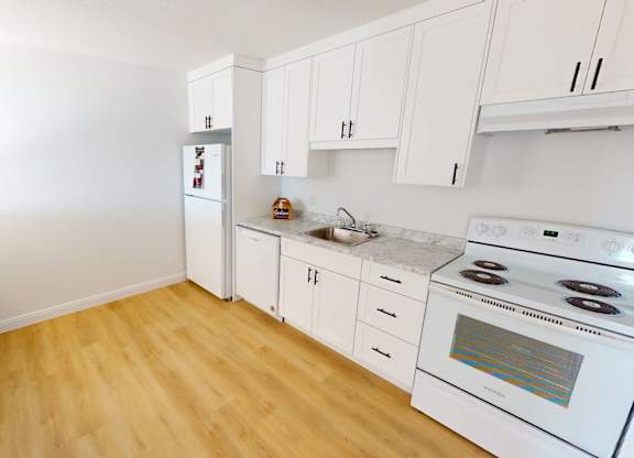 A kitchen with white appliances and wooden floors.