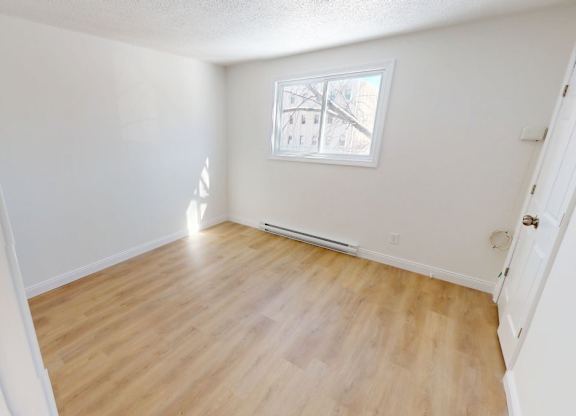A room with wooden flooring and a small window.