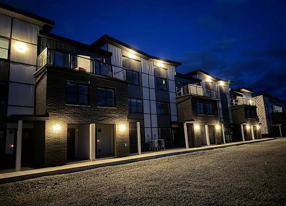 A row of modern townhouses are lit up at night.