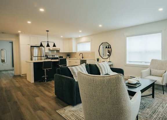 A modern living room with a kitchen area in the background.