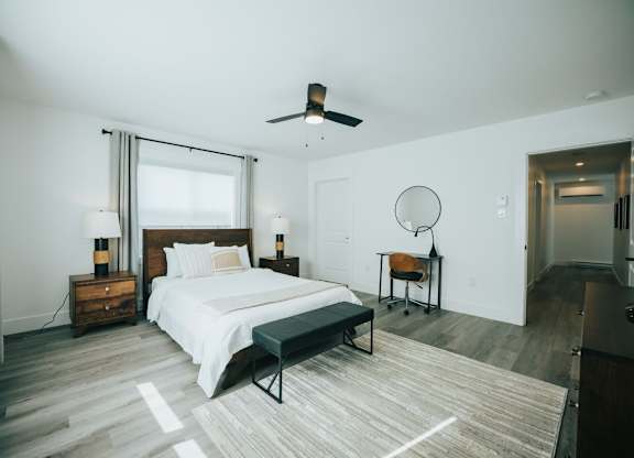 A bedroom with a bed, a chair, and a ceiling fan.