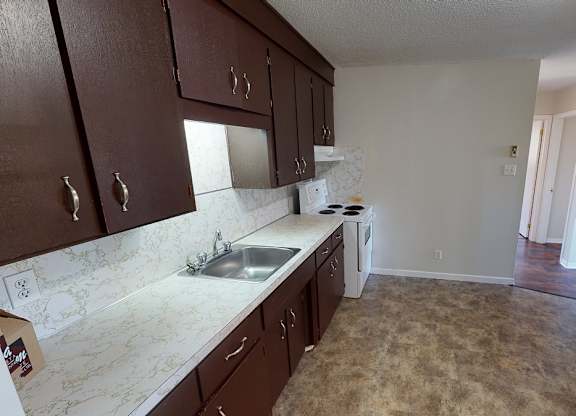A kitchen with brown cabinets and a white sink.