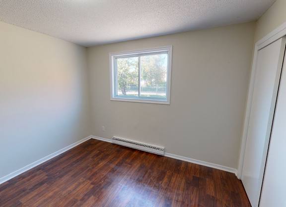 A room with a window and wooden flooring.