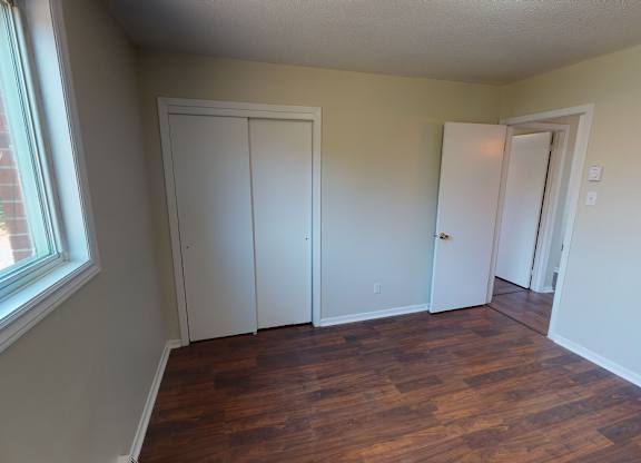 A room with a window and a wooden floor.
