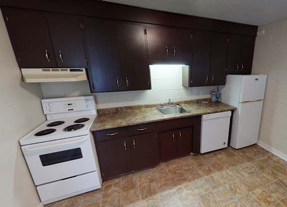 A kitchen with white appliances and brown cabinets.
