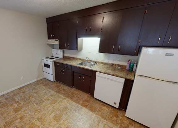 A kitchen with brown cabinets and white appliances.