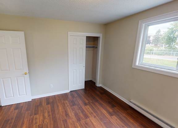 A room with wood floors and two white doors.