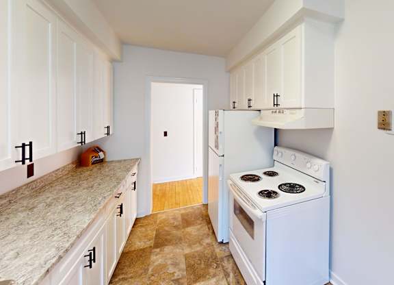 A kitchen with a white stove and cabinets.