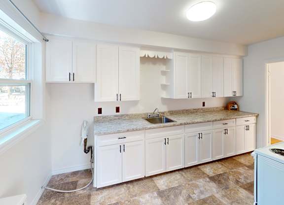 A kitchen with white cabinets and a marble countertop.