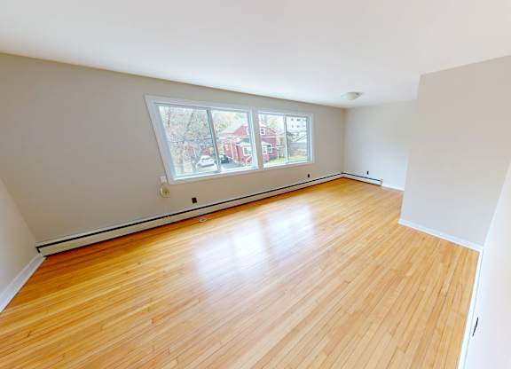 A room with wooden floors and a window overlooking a street.