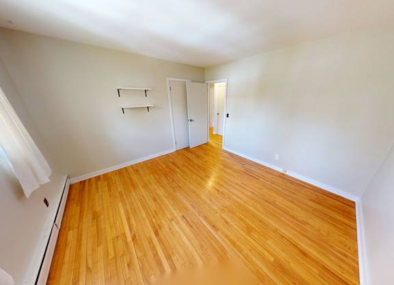 A room with wooden flooring and white walls.