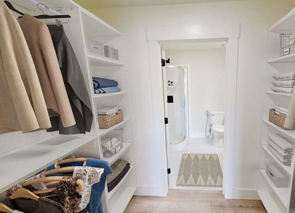 A walk-in closet with clothes and towels.