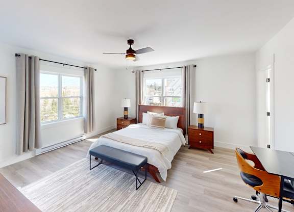 A bedroom with a bed, a chair, and a ceiling fan.
