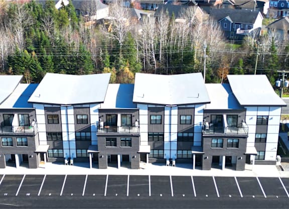 A parking lot in front of a building with grey and white exterior.