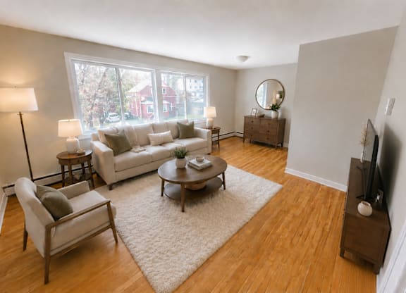 A living room with a white couch, a wooden coffee table, and a large window.