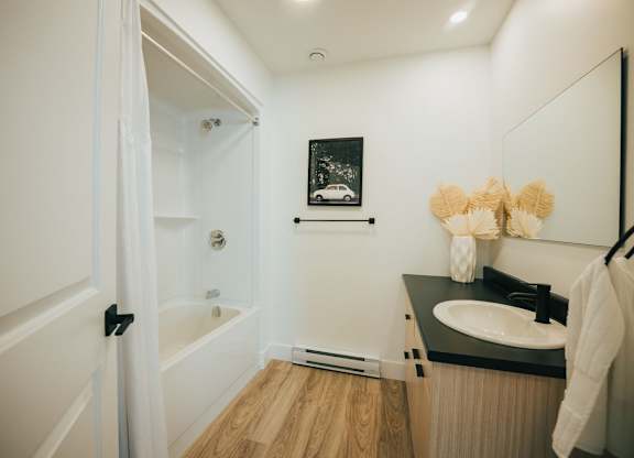 A bathroom with a sink, mirror, and a shower.