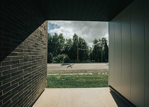 A view from a building looking out to a grassy area with trees.
